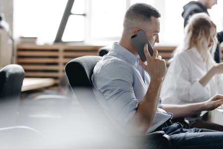 Beautiful woman and guy dressed in office style clothes are working sitting at desks in the light modern office equipped with modern office equipmentの写真素材