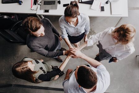 Team Building. The group of colleagues stand in a circle folded their hands together on each other...