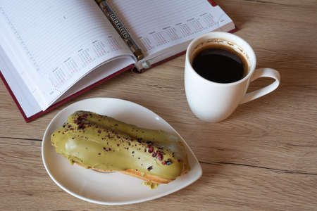 planer eclair and black coffee on table.