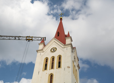 Church tower and construction crane on cloudy sky background.の写真素材