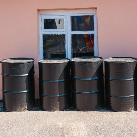 Large black metal barrels stand in a row.