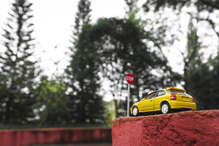 A yellow toy car meets a stop sign in the park, after some edits.の写真素材