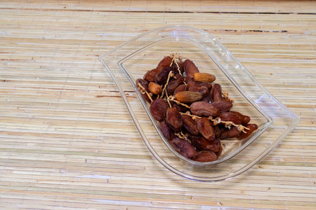 Dried dates in a transparent plastic box on a bamboo background. After some edits.