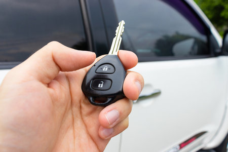 Car key in hand with car on the background. Car stuff concept. After some edits.