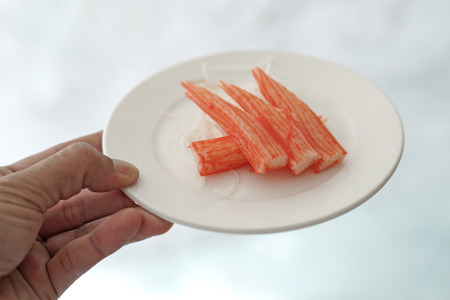 human hand hold imitation crab sticks plateの写真素材