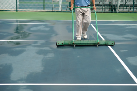 cleaning crew drying tennis court after rainの写真素材