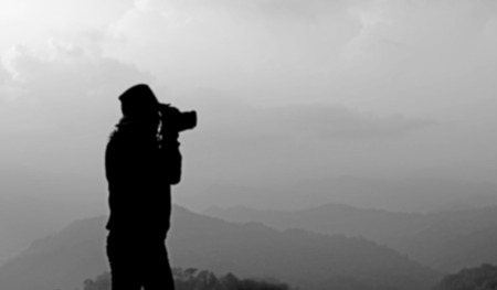 blurry silhouette photographer is taking photos of misty mountain hills landscapeの写真素材