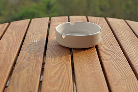 empty white ashtray on a wooden tableの写真素材