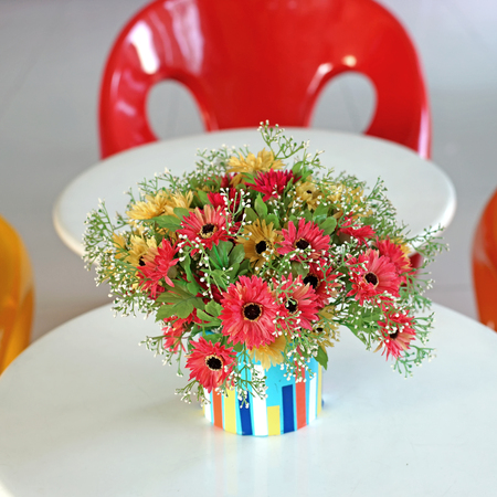 colorful artificial flower in flowerpot on the tableの写真素材