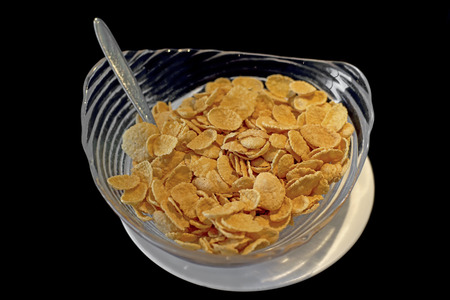 cereal corn flakes in a glass bowl on black background