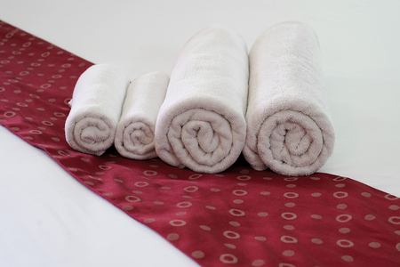 white towels rolled and piled on bedの写真素材
