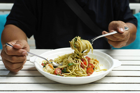 closeup of man hands holding fork and spoon during eating spaghettiの写真素材