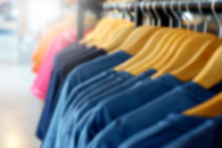 blurry photo of  shirts  hanging on rack in the storeの写真素材