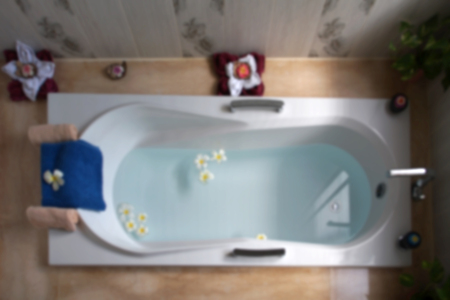blurry photo, top view of bathtub with towel and frangipani flower