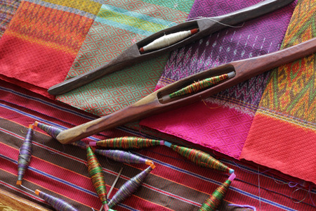 colorful bobbins and wooden bobbin on silk fabric, traditional weaving of Thai silk