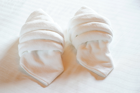 white towels rolled and piled on bedの写真素材