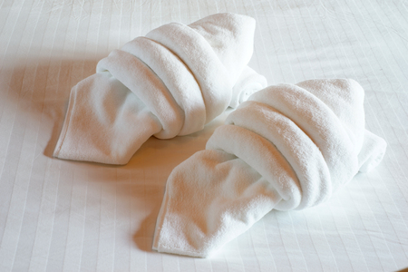white towels rolled and piled on bedの写真素材