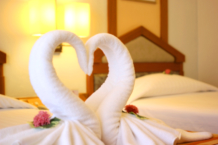 blurry photo of swans shaped of white towel on the bedの写真素材