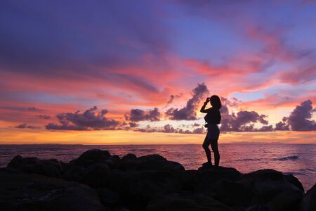 silhouette of women standing on the beach beautiful sky backgroundの写真素材
