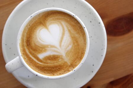 cup of hot latte art coffee on wooden table