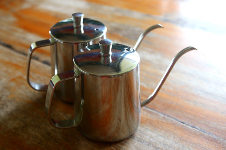 stainless steel coffee drip kettle jug on wooden tableの写真素材