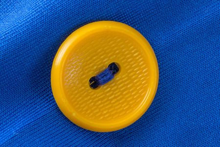 yellow button on blue cloth in macroの写真素材