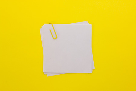 white sheet of paper with yellow paper clip on a yellow backgroundの写真素材