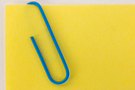 blue paper clip on a yellow sheet of paper macroの写真素材