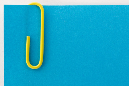 yellow paper clip on a blue sheet of paper macroの写真素材