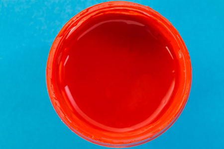 jar with red gouache on a blue background closeupの写真素材