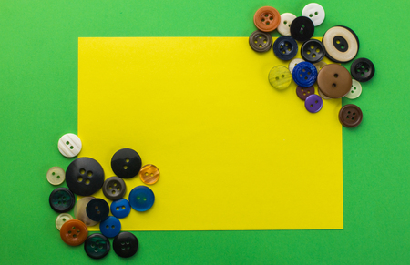 buttons and yellow sheet of paper on a green backgroundの写真素材