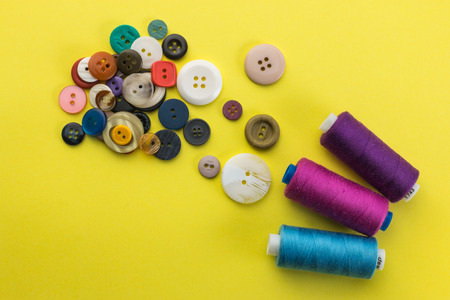 buttons and thread on a yellow backgroundの写真素材