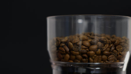 Coffee beans in the grinder bowl on a black backgroundの写真素材