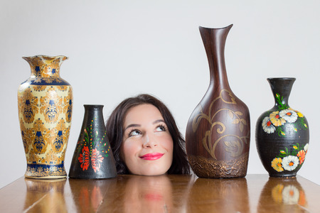 Girl head with vases on table smiling at one of the vasesの写真素材