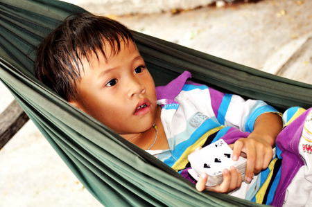 Nha Trang, VIETNAM - SEPTEMBER 28,2013: Vietnamese boy lying in a hammock with a deck of cards in the city of Nha Trang.Vietnamのeditorial素材