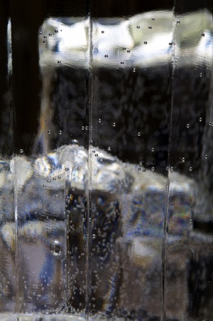 part of glass with ice cubes and liquid with bubbles macro blurの写真素材