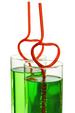 two glasses with green beverage and drinking straws isolated on white backgroundの写真素材