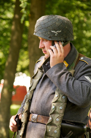 man in form of nazi sniper speaks by the mobile phone near a tree on celebration of 750 anniversary of Guryevsk (Neuhausen O.P.) on June 30, 2012 in Guryevsk, Kaliningradskaya oblast, Russiaのeditorial素材