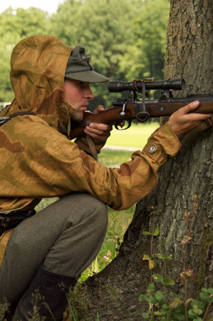 man in form of nazi sniper aims near a tree on celebration of 750 anniversary of Guryevsk (Neuhausen O.P.) on June 30, 2012 in Guryevsk, Kaliningradskaya oblast, Russiaのeditorial素材