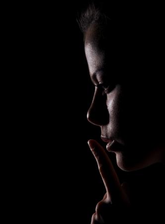 Young Woman Gesturing For Being Quiet, Shows Silence Sign In Dark Backgroundの写真素材