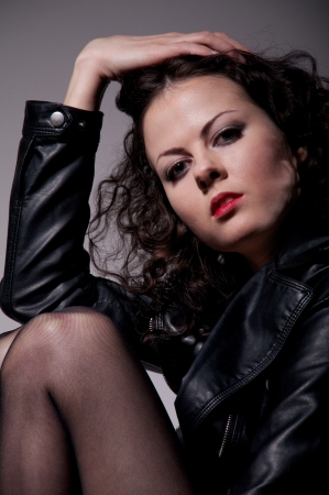 pretty girl in leather jacket and stockings on gray backgroundの写真素材