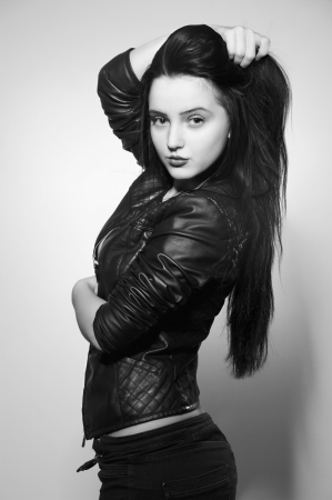 pretty brunette girl in leather jacket smiling at gray background monochrome imageの写真素材