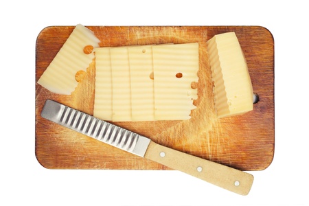 pieces of cut cheese and special cheese knife on a chopping boardの写真素材