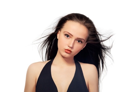Close up of a beautiful girl with long dark flying hair with serious pensive look on her face staring on camera isolated on white background  の写真素材