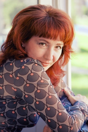 mature woman with red hairs smiling looking on cameraの写真素材