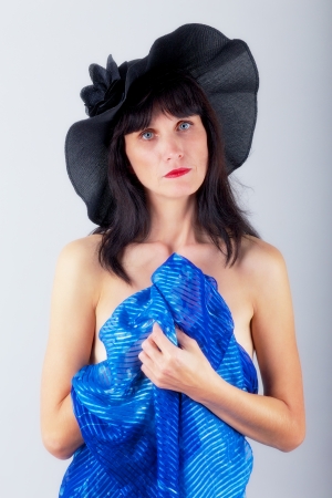 mature serious woman with bared shoulders with blue veil in black hatの写真素材