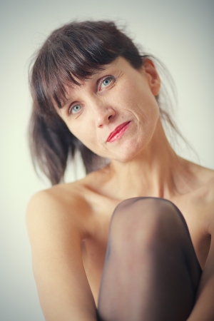 smiling pensive mature woman with bared shoulders on white backgroundの写真素材