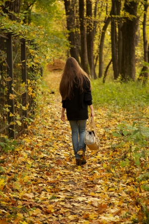 girl walks on leaves in autumn parkの写真素材