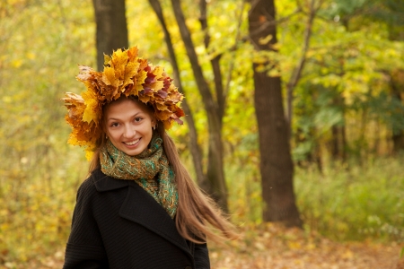 girl in yellow leaves crown smiling looks at cameraの写真素材