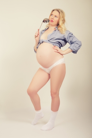 thinking pregnant woman posing with serving spoonの写真素材